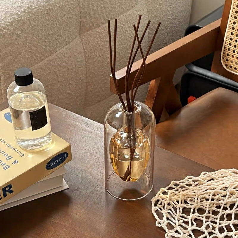 Sculptural glass reed diffuser styled on a bathroom vanity with eucalyptus and candles