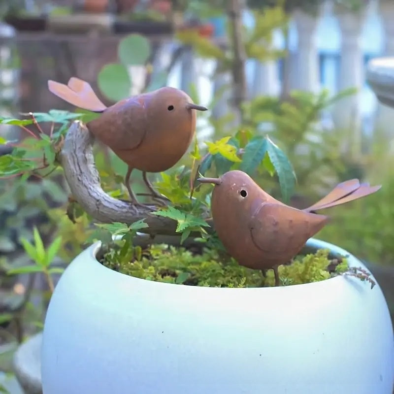 Rustic iron bird garden decoration with weathered finish standing among garden plants