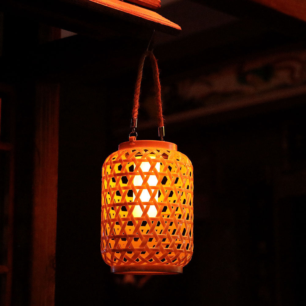 Solar powered rattan hanging lantern glowing at dusk in a garden setting