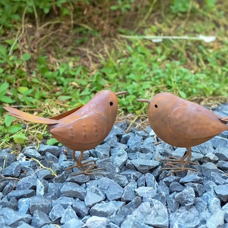 Rustic metal bird ornament among succulents and terracotta pots on a garden shelf