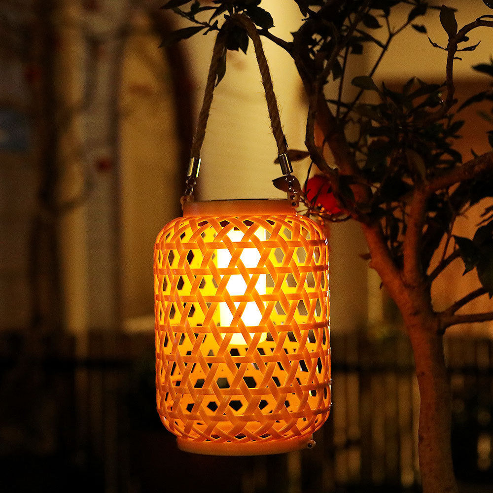 Solar rattan lantern illuminated at night surrounded by garden greenery