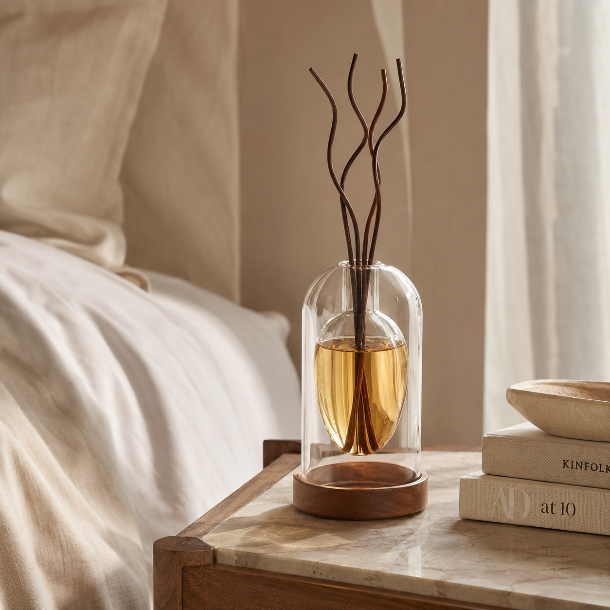 Two sculptural glass reed diffusers side by side in a bedroom lifestyle setting